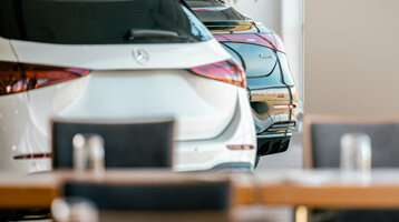 Zwei Autos parken im Innenbereich des ATLANTIC Hotel Galopprennbahn Bremen, im Vordergrund unscharfe Tische.