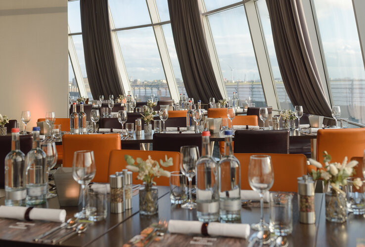 Elegant restaurant in the ATLANTIC Hotel Sail City with set tables and panoramic windows overlooking the harbor.