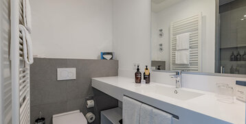 Modern bathroom with washbasin, mirror, towel rail, WC and care products at the ATLANTIC Grand Hotel Travemünde.