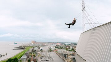 Frau schaukelt über der Aussichtsplattform auf dem ATLANTIC Hotel Sail City.