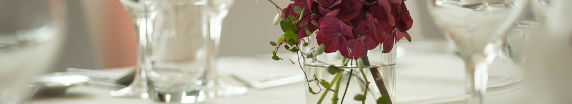Floral decoration for a celebration at the ATLANTIC Hotel Kiel Elegant table decoration at the ATLANTIC Hotel Kiel with flower arrangement and glasses on a white tablecloth.
