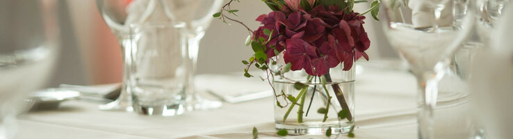 Elegant table decoration at the ATLANTIC Hotel Kiel with flower arrangement and glasses on a white tablecloth.