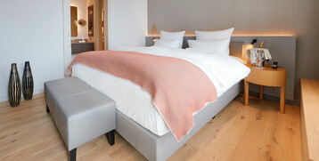 Modern hotel room with comfortable double bed, wooden floor and stylish furnishings at the ATLANTIC Grand Hotel Bremen.