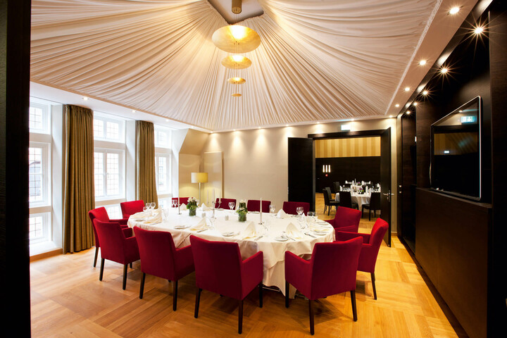 Gedeckter Tisch im Zelt des ATLANTIC Grand Hotel Bremen Eleganter Veranstaltungsraum mit runder Tafel, roten Stühlen und stilvoller Beleuchtung im ATLANTIC Grand Hotel Bremen.