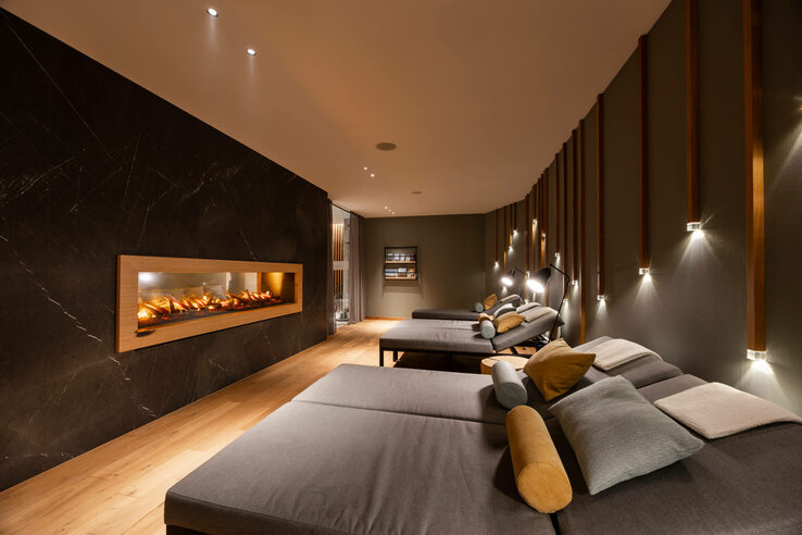 Gemütlicher Ruheraum im ATLANTIC Hotel Heidelberg mit Liegen, Kamin und stimmungsvoller Beleuchtung.