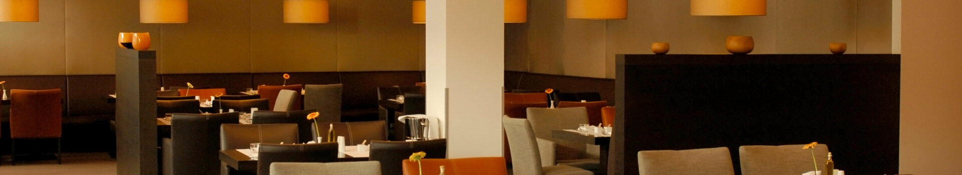 Modernes Hotelrestaurant mit elegant gedeckten Tischen, bequemen Stühlen und warmem Licht im ATLANTIC Hotel Lübeck.