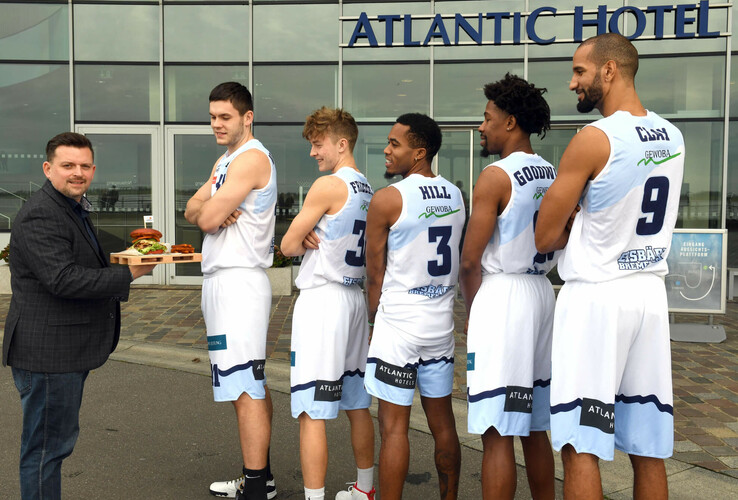 Man with tray and basketball player in front of the ATLANTIC Hotel Sail City in Bremerhaven.