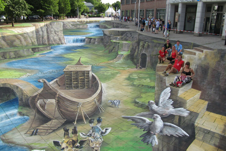 3D street art with Noah's Ark, animals and a waterfall, people sitting on a painted wall.