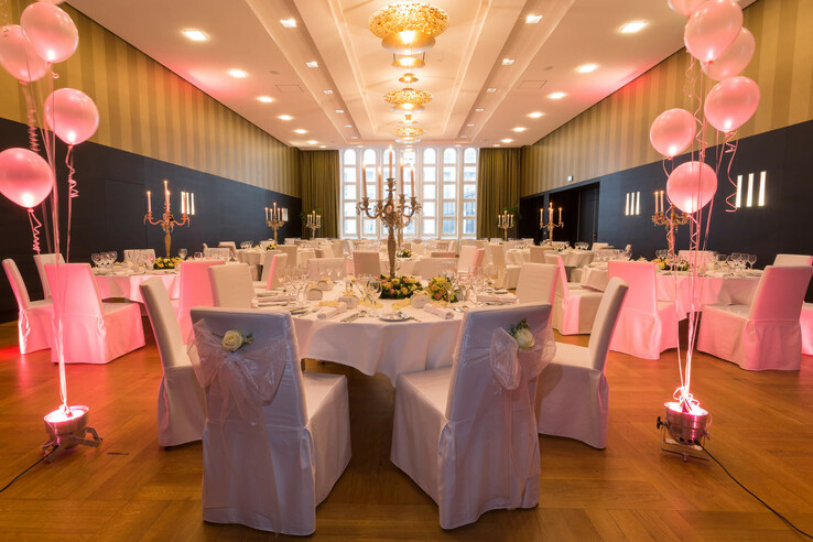 Eleganter Bankettsaal im ATLANTIC Grand Hotel Bremen, dekoriert mit weißen Tischdecken, Kerzenleuchtern und rosa Luftballons.