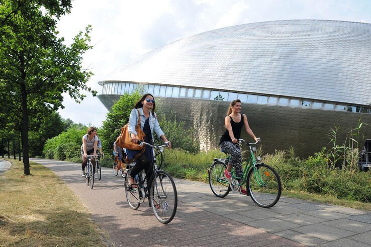 People cycling near the Universum Bremen, surrounded by green nature.