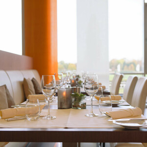 Modernes Restaurant mit elegant gedeckten Tischen, weißen Stühlen und großen Fenstern im ATLANTIC Hotel Galopprennbahn.