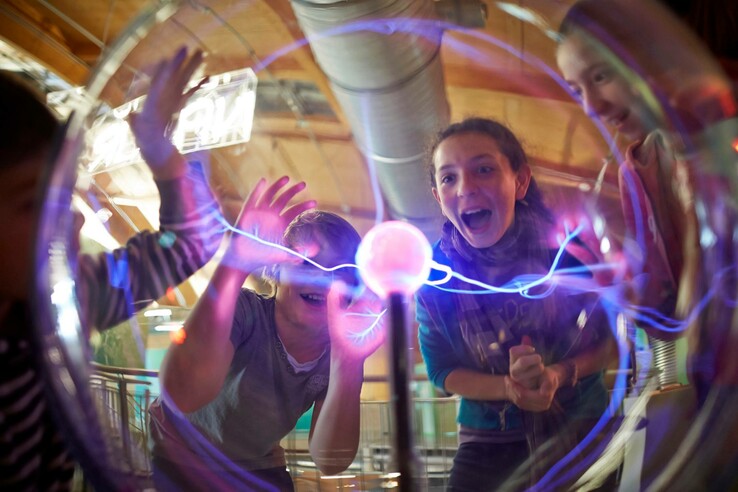 Kinder interagieren begeistert mit einer Plasmakugel im Universum Bremen.