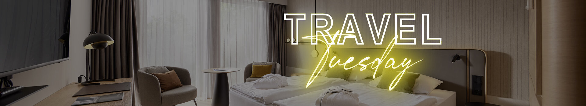 Modern hotel room with double bed, desk, armchair and large windows, text "Travel Tuesday" in neon.
