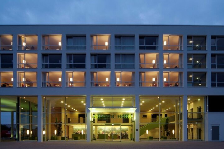 ATLANTIC Hotel Galopprennbahn Bremen bei Nacht Moderne Hotel-Fassade bei Dämmerung, beleuchtete Fenster und Eingang des ATLANTIC Hotel Galopprennbahn in Bremen.