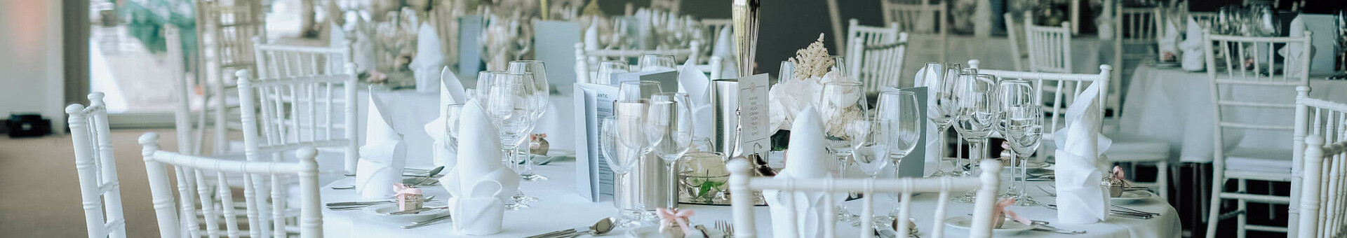 Celebrate at the ATLANTIC Hotels Elegant banquet hall with tables set in white, flower arrangements and candlesticks.