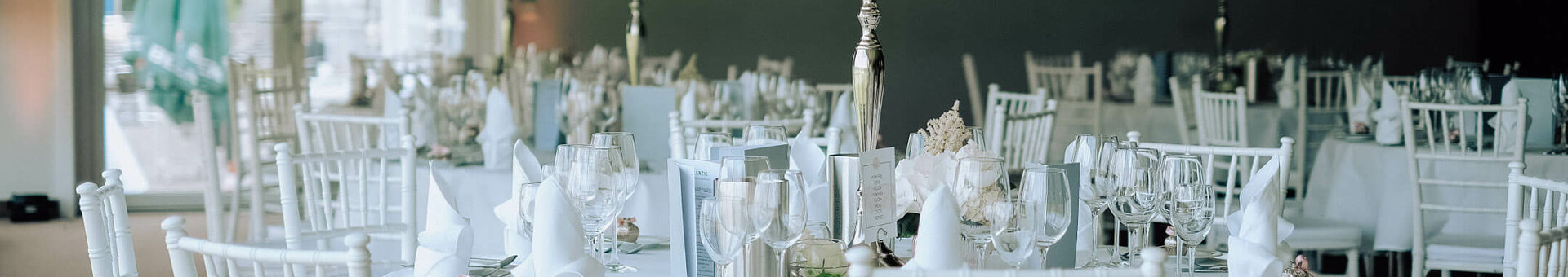 Eleganter Bankettsaal mit weiß gedeckten Tischen, Blumenarrangements und Kerzenleuchtern.