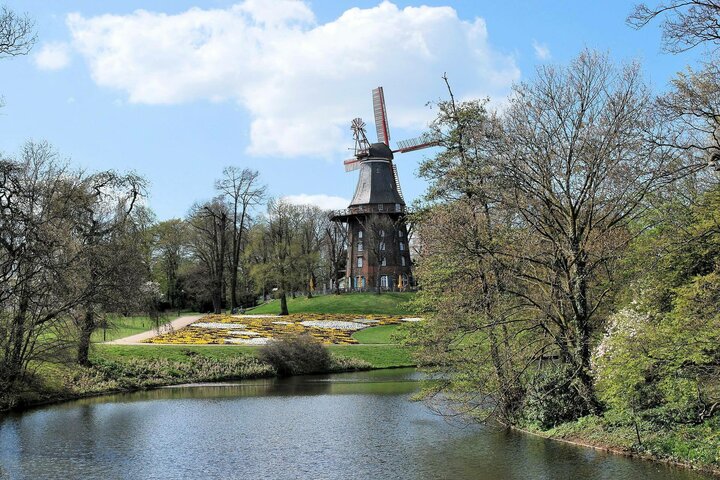 Mill in the park in Bremen Historic windmill in a green park, surrounded by trees and a small pond.