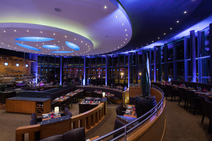 Modern restaurant with elegant lighting and panoramic windows at the ATLANTIC Hotel Airport Bremen.