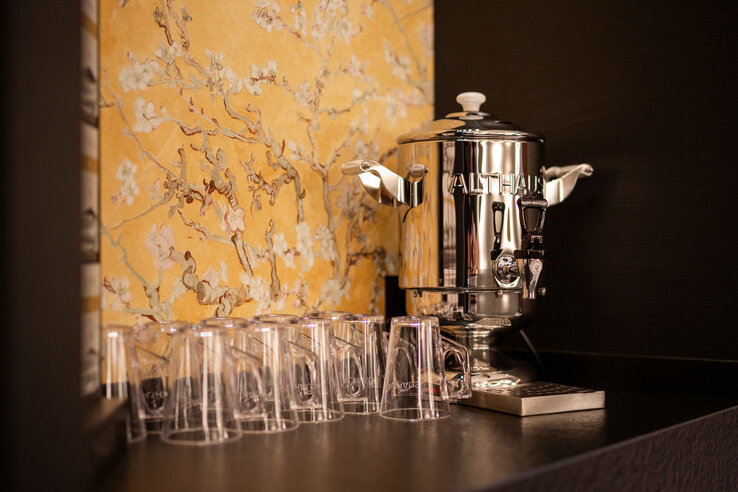 Silberner Samowar mit Gläsern vor blumiger Tapete im ATLANTIC Hotel Heidelberg.