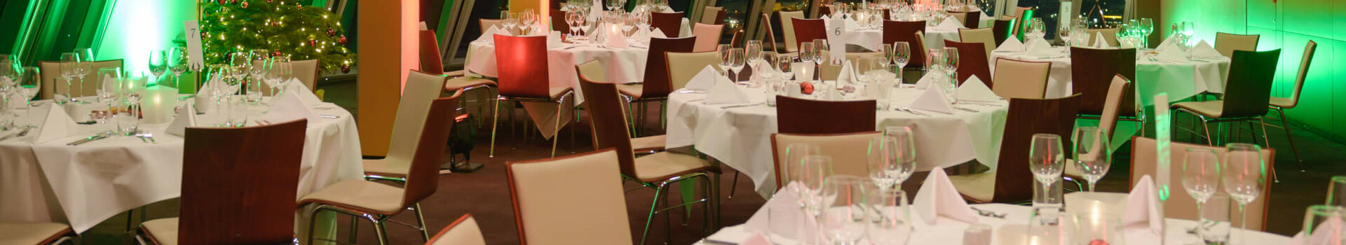 Festlich gedeckter Bankettsaal im ATLANTIC Hotel Sail City, Bremerhaven, mit weihnachtlicher Beleuchtung und geschmücktem Baum.