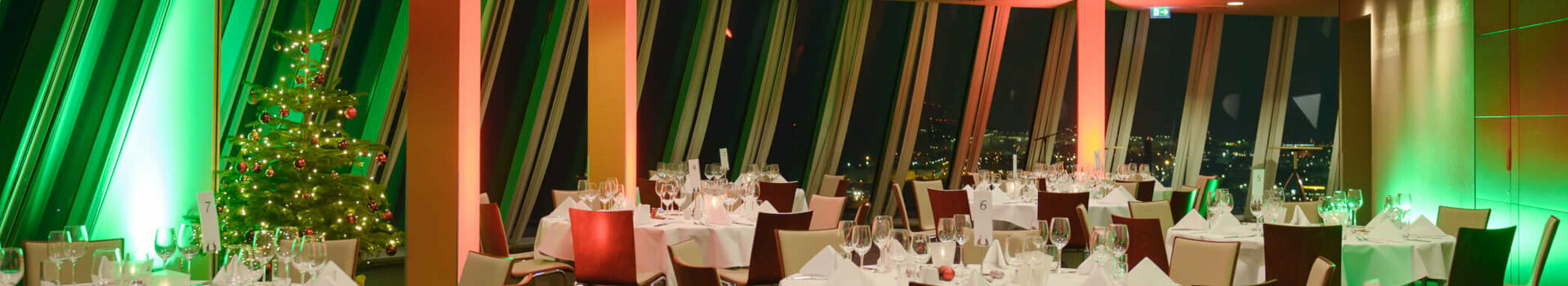 Festively decorated banquet hall in the ATLANTIC Hotel Sail City, Bremerhaven, with Christmas lighting and a decorated tree.