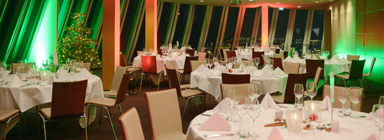 Festively decorated banquet hall in the ATLANTIC Hotel Sail City, Bremerhaven, with Christmas lighting and a decorated tree.