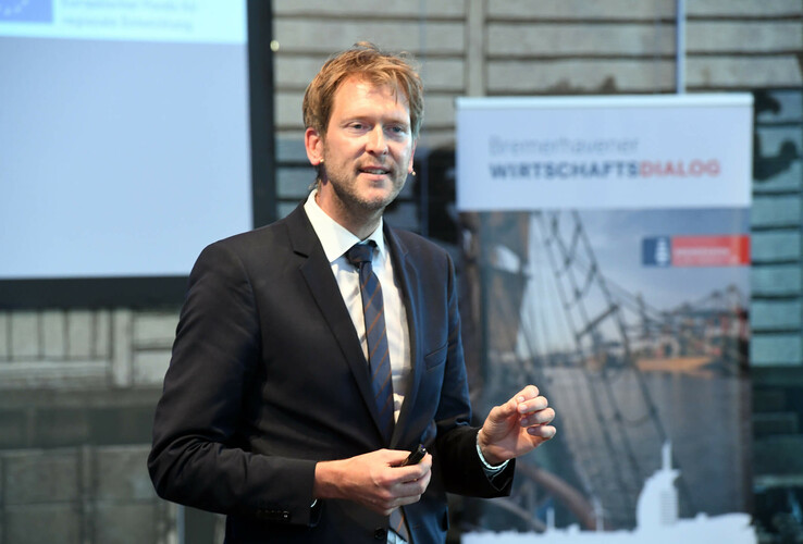Ein Mann im Anzug hält eine Präsentation im ATLANTIC Hotel Sail City in Bremerhaven.