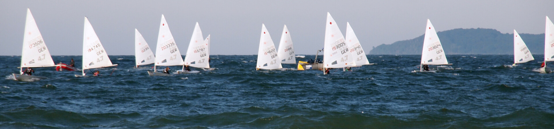 Segelboote auf der Ostsee bei Travemünde, blauer Himmel und Wellen im Vordergrund.