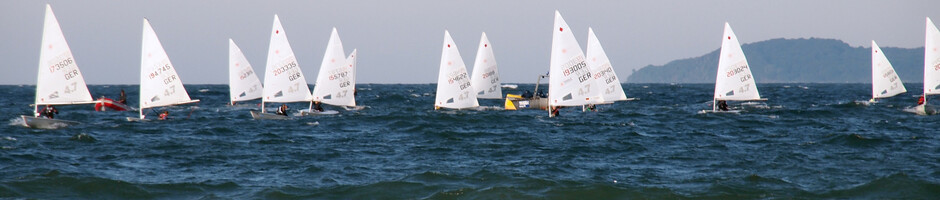 Segelboote auf der Ostsee bei Travemünde, blauer Himmel und Wellen im Vordergrund.