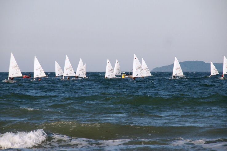 Segelboote auf der Ostsee bei Travemünde, blauer Himmel und Wellen im Vordergrund.