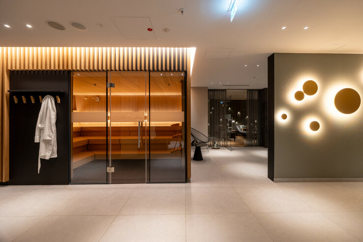Modern wellness area in the ATLANTIC Hotel Heidelberg with sauna, decorative wall lights and cozy seating area.