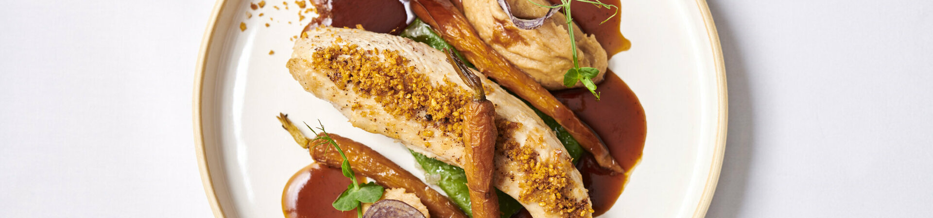 Gourmet dish with chicken breast, carrots, puree and jus, artfully served on a white plate.