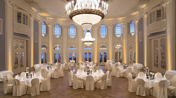 ATLANTIC Grand Hotel Travemünde – historic ballroom Elegant ballroom with round, white-clothed tables, high windows and large chandeliers in the ATLANTIC Grand Hotel Travemünde.