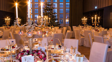 Eleganter Festsaal im ATLANTIC Grand Hotel Bremen, festlich gedeckte Tische mit Kerzenleuchtern und Weihnachtsbaum.