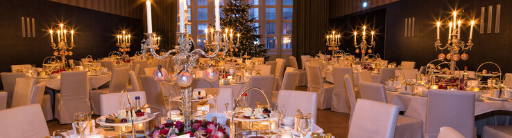 Eleganter Festsaal im ATLANTIC Grand Hotel Bremen, festlich gedeckte Tische mit Kerzenleuchtern und Weihnachtsbaum.