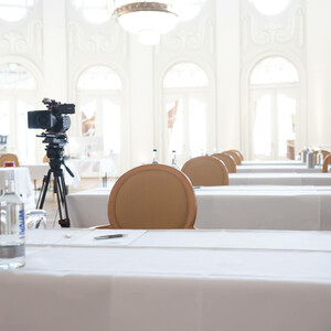 Heller Konferenzraum im ATLANTIC Grand Hotel mit gedeckten Tischen, Kamera und eleganten Fenstern.