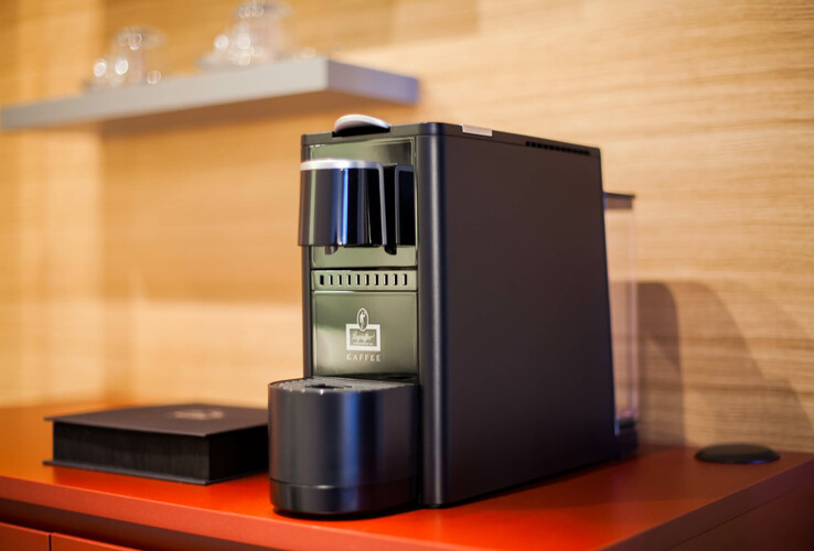 Coffee machine on a red shelf in the ATLANTIC Hotel Airport Bremen, with cups in the background.