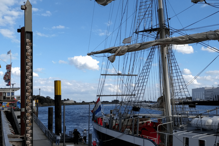 Segelschiff in Vegesack, Bremen, mit Wasserstandsanzeige und blauem Himmel im Hintergrund.