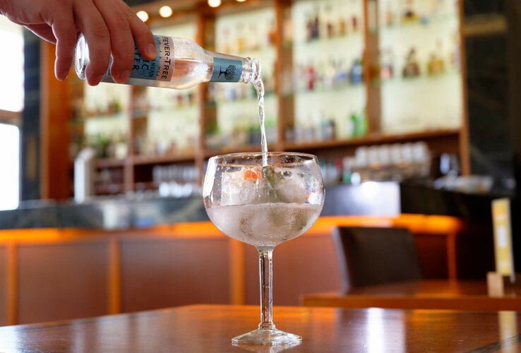 Ein Glas wird in einer stilvollen Bar mit Tonic Water gefüllt.