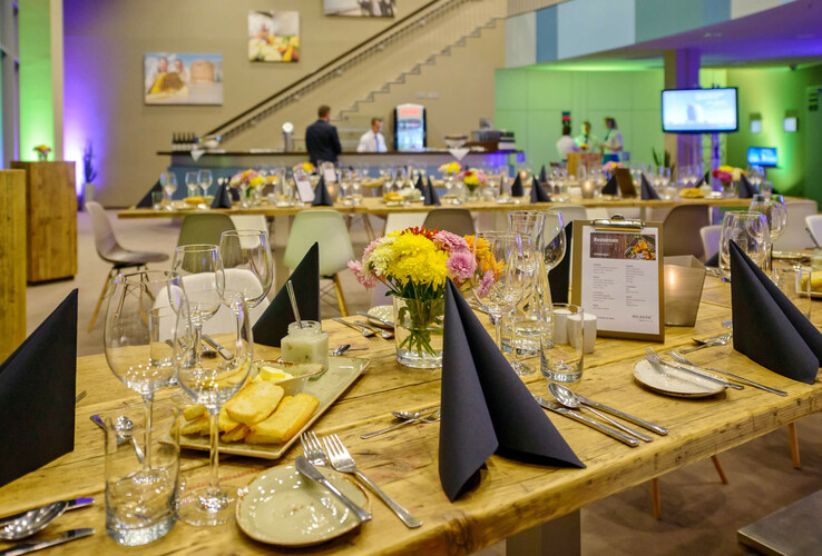 Elegantes Restaurant im ATLANTIC Hotel Sail City, Bremerhaven. Stilvoll gedeckte Tische mit Blumen und Kerzen.