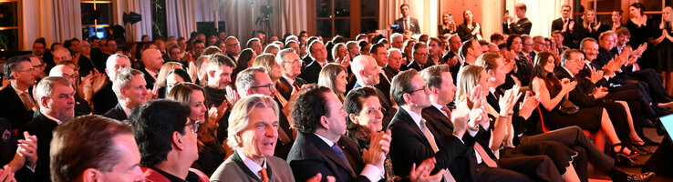 ATLANTIC Grand Hotel Travemünde Preisverleihung Eine große Gruppe von Menschen in formeller Kleidung applaudiert in einem elegant beleuchteten Veranstaltungsraum.