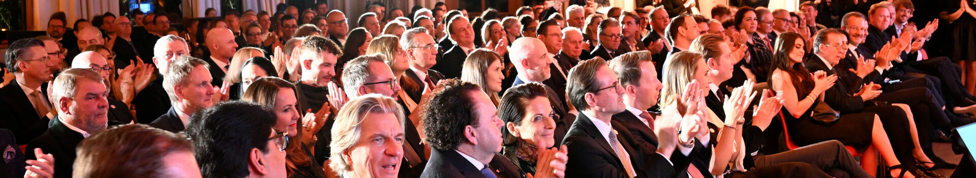 ATLANTIC Grand Hotel Travemünde Preisverleihung Eine große Gruppe von Menschen in formeller Kleidung applaudiert in einem elegant beleuchteten Veranstaltungsraum.
