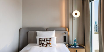 A modern single bed and bedside table with a bottle of water.