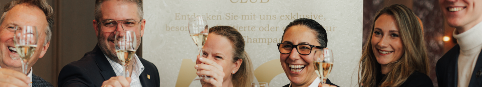 Menschen halten lachend ein Glas Champagner.