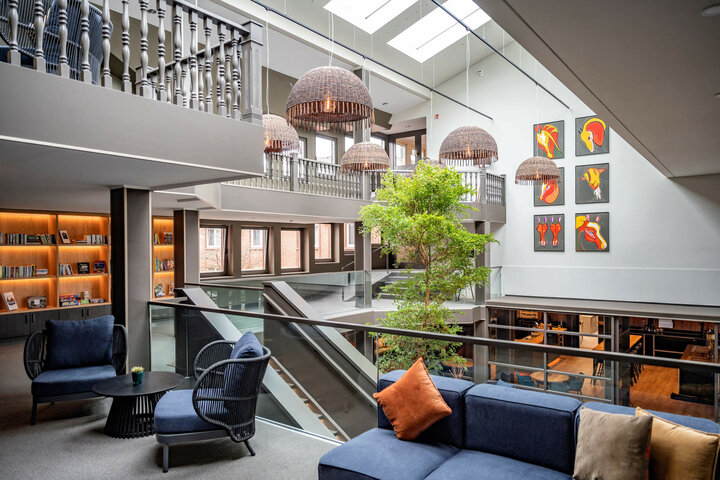 Bright atrium of the ATLANTIC Hotel Landgut Horn with seating area, works of art, large windows and plants.