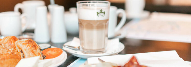 Breakfast table at the ATLANTIC Hotel Lübeck with coffee, pastries and fresh tomatoes.
