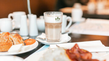 ATLANTIC Hotel Lübeck Frühstück Frühstückstisch im ATLANTIC Hotel Lübeck mit Kaffee, Gebäck und frischen Tomaten.