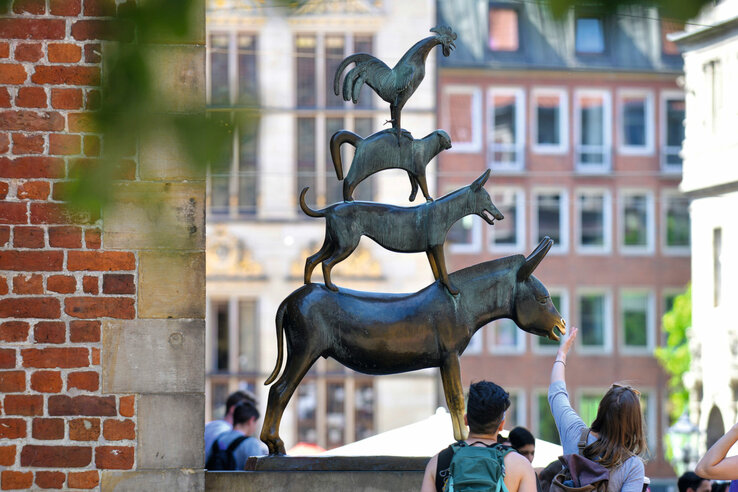 Skulptur der Bremer Stadtmusikanten mit Esel, Hund, Katze und Hahn, umgeben von Touristen in der Innenstadt Bremens.