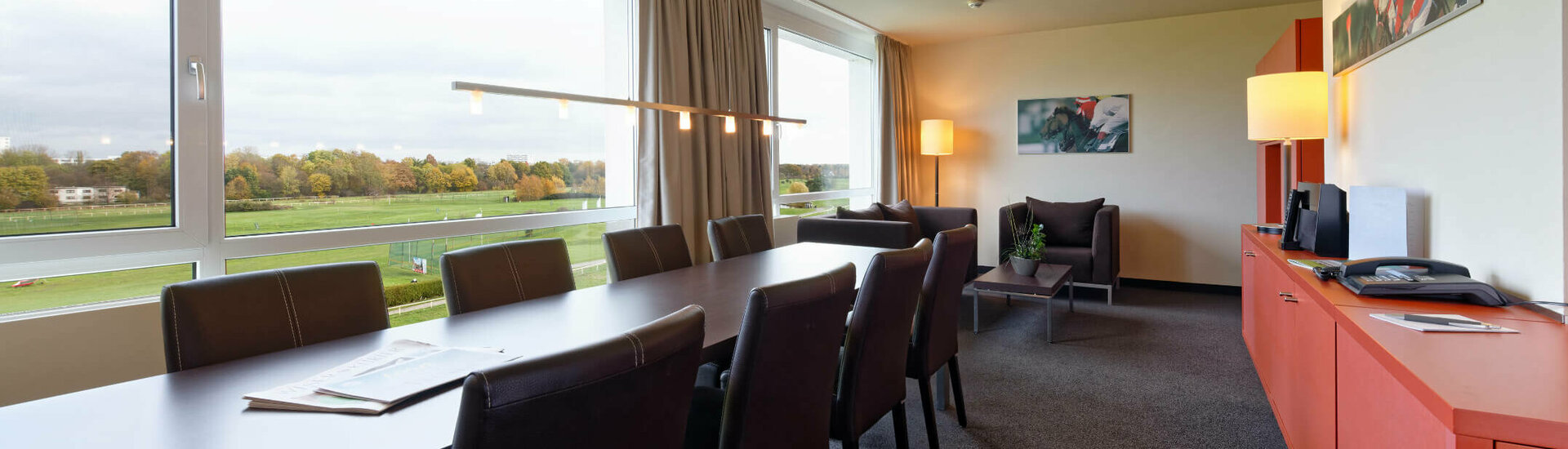 Studio | ATLANTIC Hotel Galopprennbahn Bright conference room in the ATLANTIC Hotel with a large table, leather armchairs and a view of the racecourse.