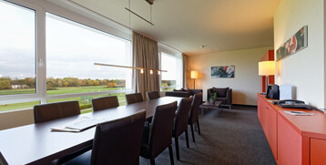 Bright conference room in the ATLANTIC Hotel with a large table, leather armchairs and a view of the racecourse.